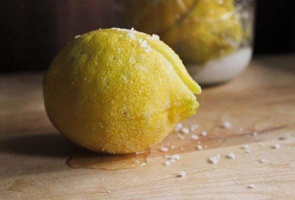 A preserved lemon sprinkled with salt on a wooden surface.