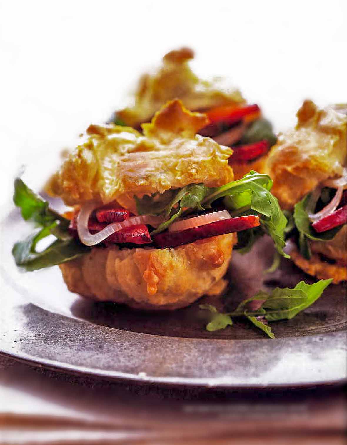 Gougeres, or cheese puffs, with arugula, bacon, and pickled onion on a metal plate