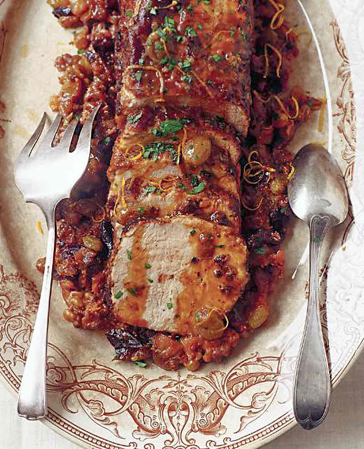 Platter with sliced pork loin topped with fall fruits including raisins, figs, apricots