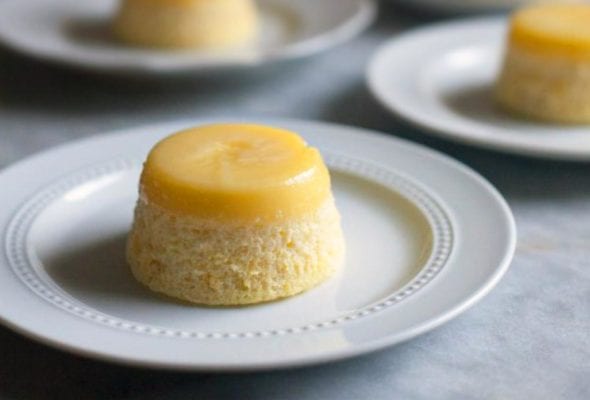 Four white plates, each topped with a lemon steamed pudding.