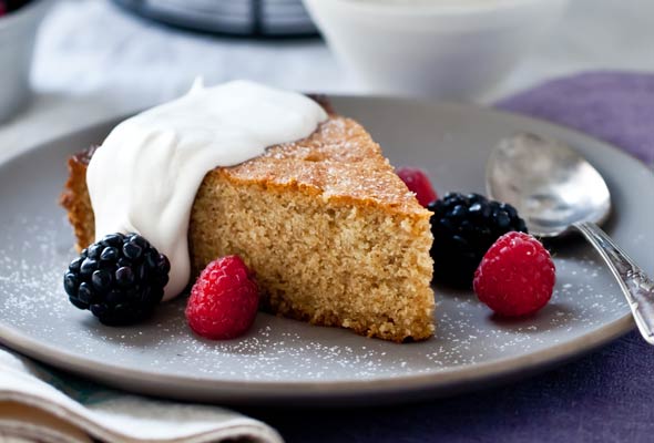 A slice of honey walnut cake, topped with whipped cream and fresh berries.