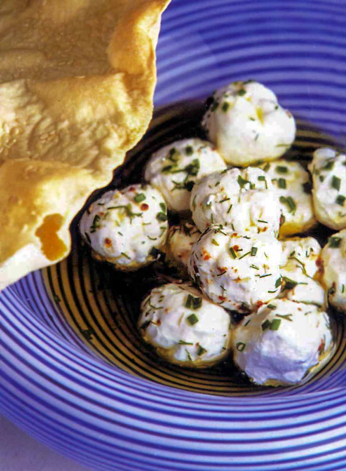 Yogurt cheese balls tossed with garlic dill oil and aleppo pepper in a bowl
