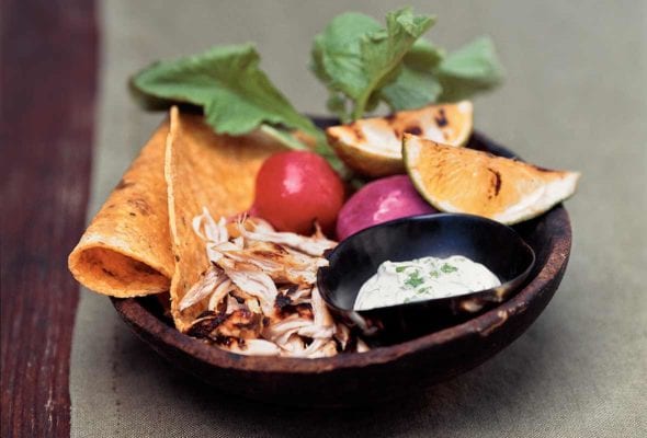 Wood bowl with tequila-lime chicken tacos, charred limes, radishes, sour cream