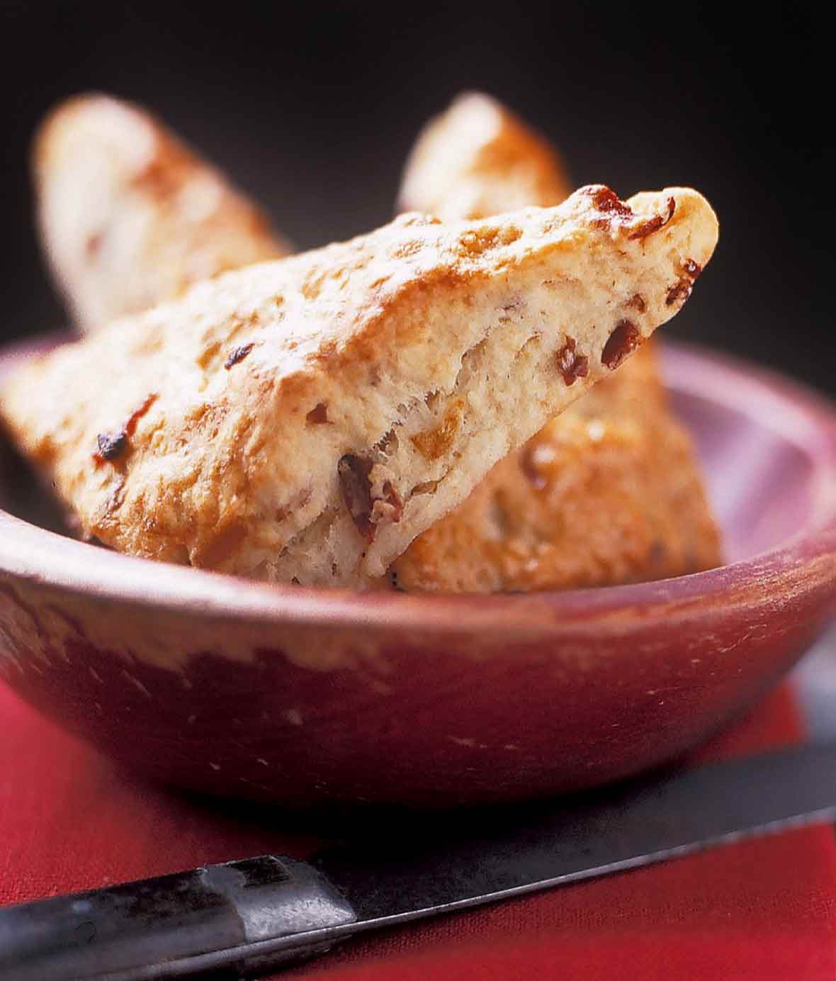 A red bowl filled with triangle-shaped bacon buttermilk scones.