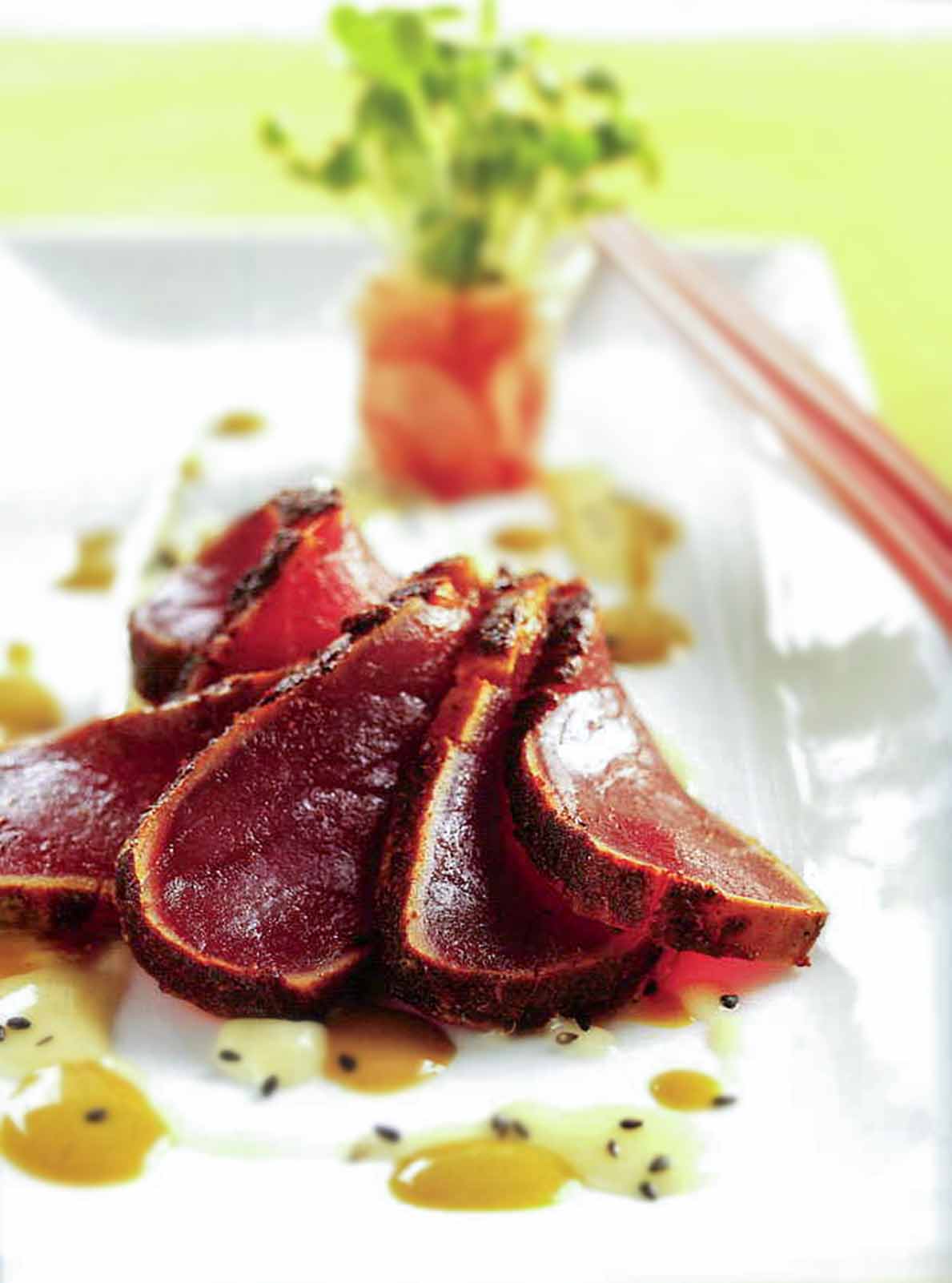 Five slices of blackened Ahi tuna with soy mustard sauce and beurre blanc dotted around them.