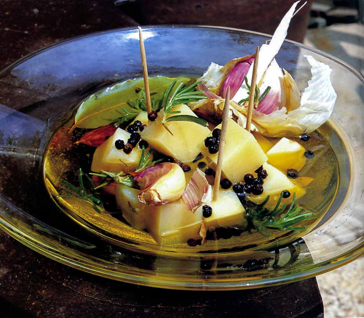 Marinated Idiazábal cheese chunks, garlic, and rosemary on a glass plate