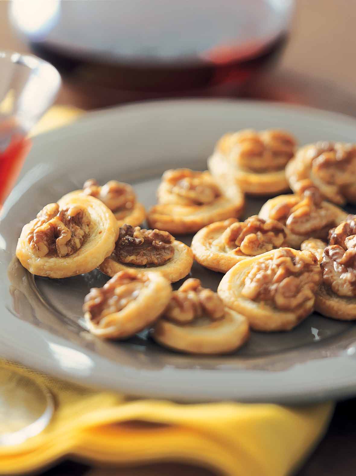 A grey plate filled with stilton pinwheels with walnuts and honey on a yellow cloth.