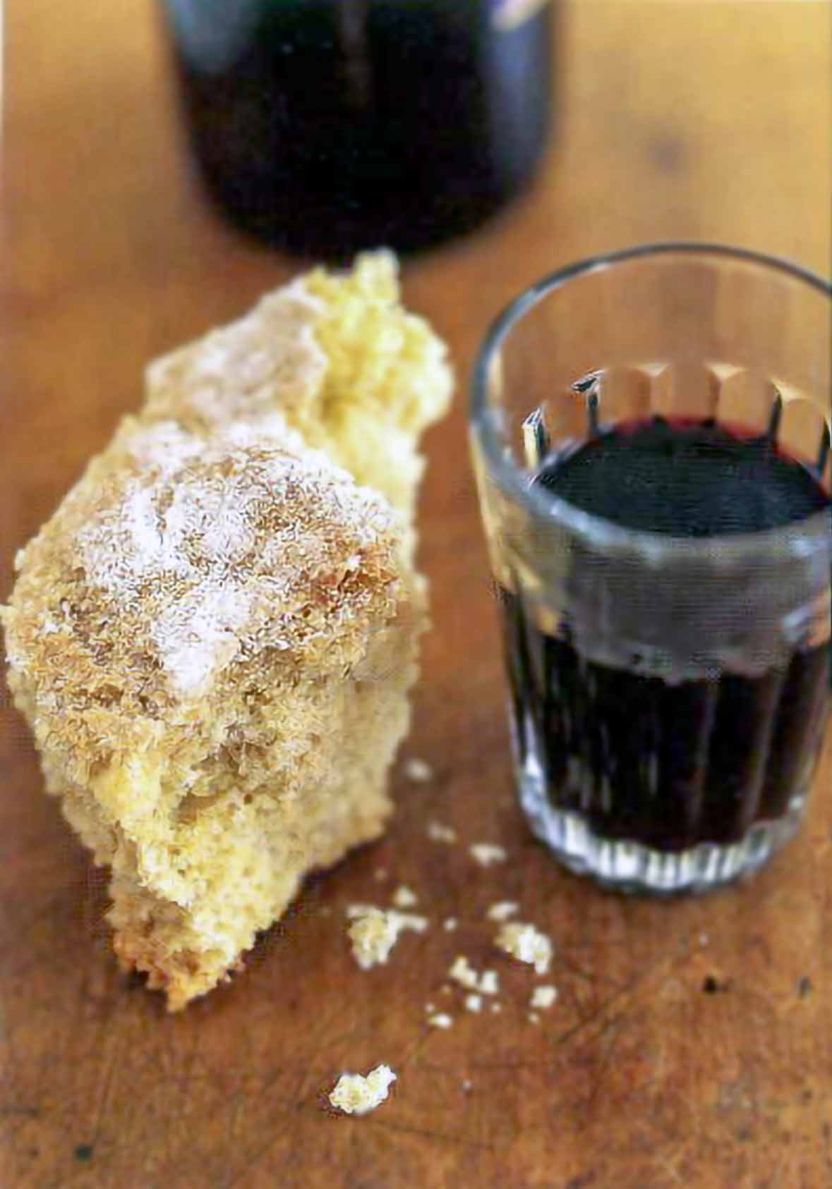 A chuck broa, or Portuguese corn bread, on a wooden table with wine nearby