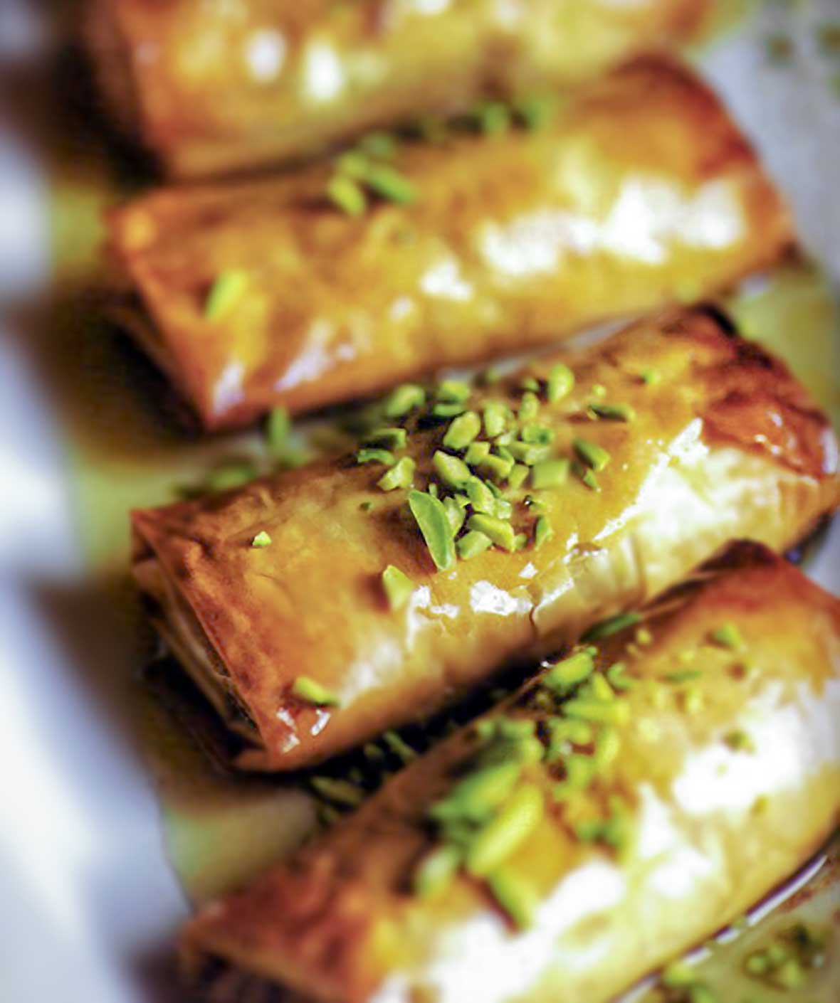 Four phyllo pastries stuffed with nuts, honey, and orange blossom water, and topped with pistachios and more honey