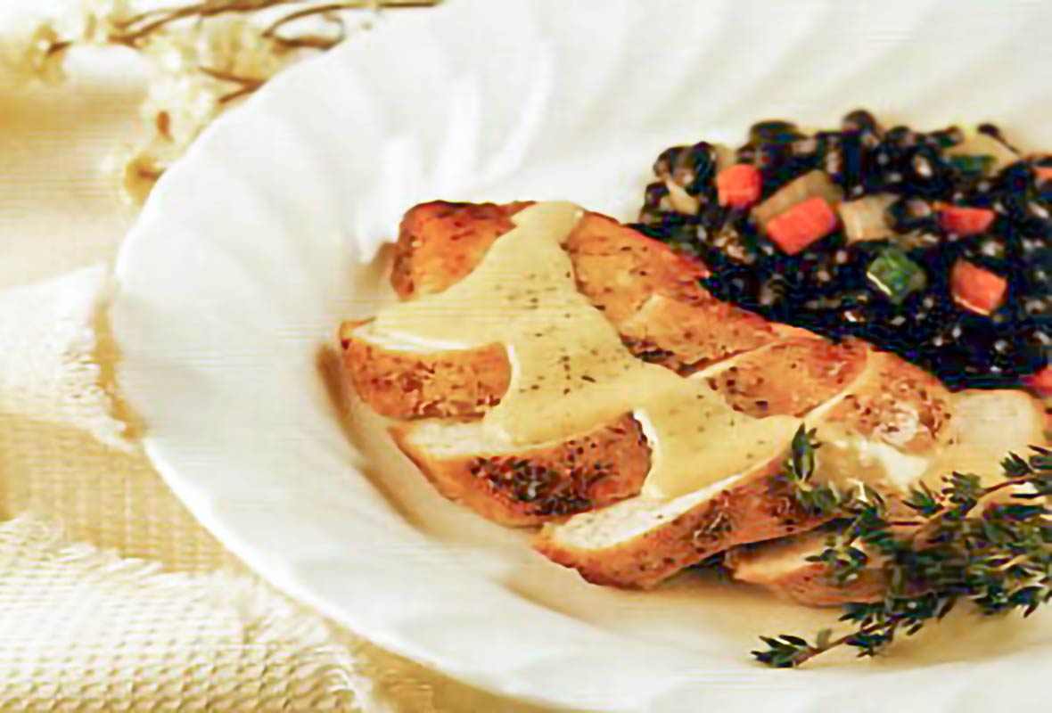 Sliced chicken breast with a goat cheese–herb sauce, chopped Swiss chard on a plate