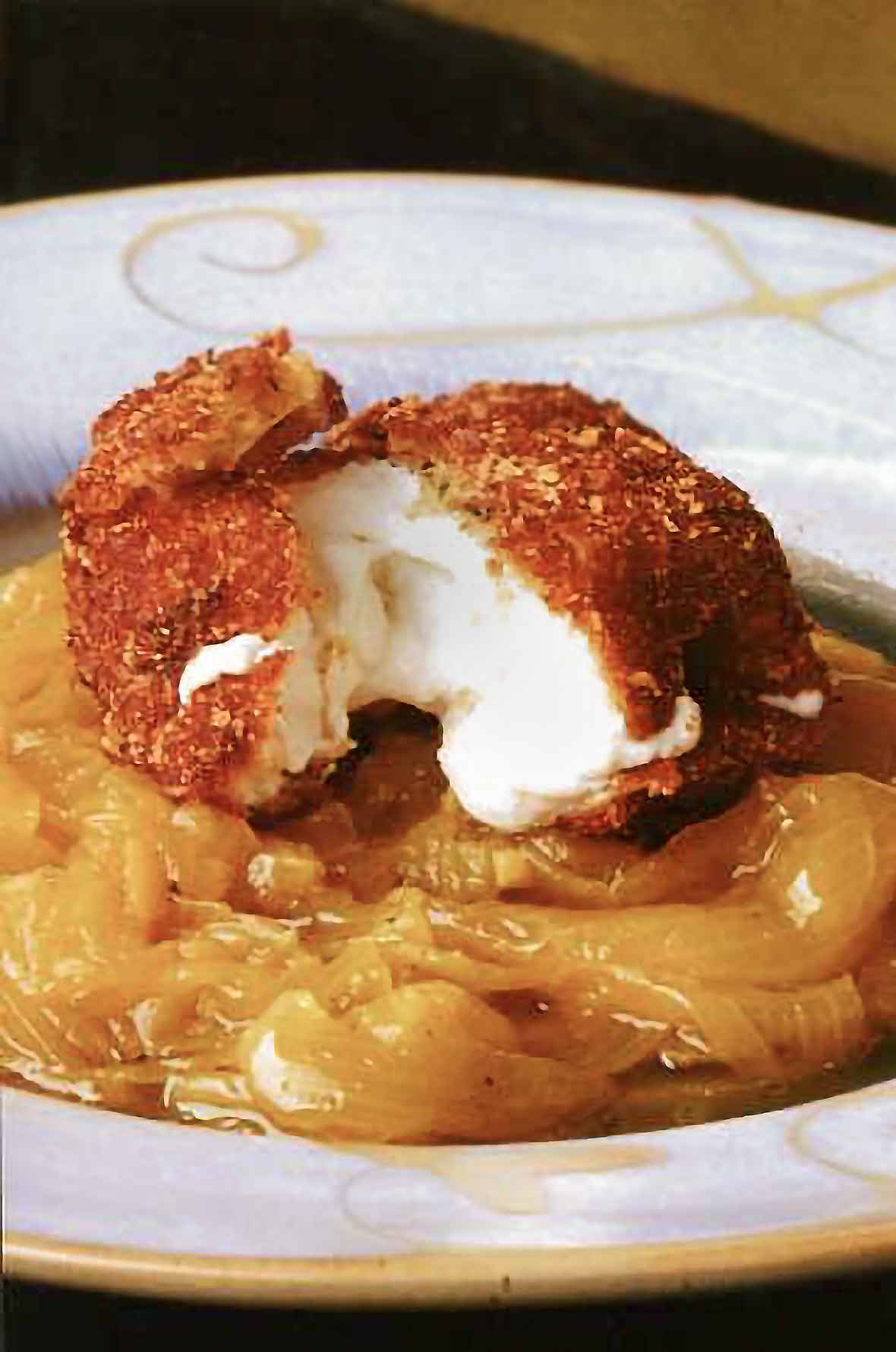 Disc of crusted fried Goat cheese with onion confit underneath, opened and cheese oozing out