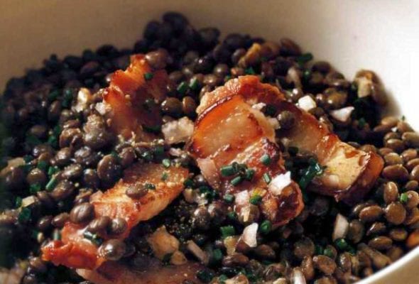 White bowl with warm lentil salad and pieces of bacon