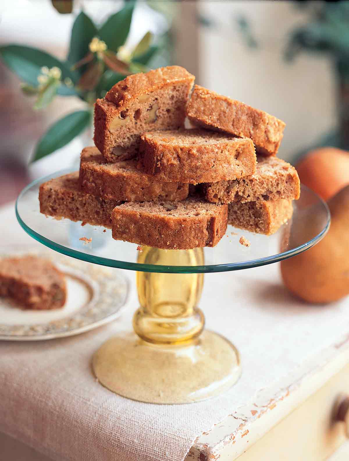A glass cake stand topped with several slices of Cornelia Walker Bailey's pear bread.