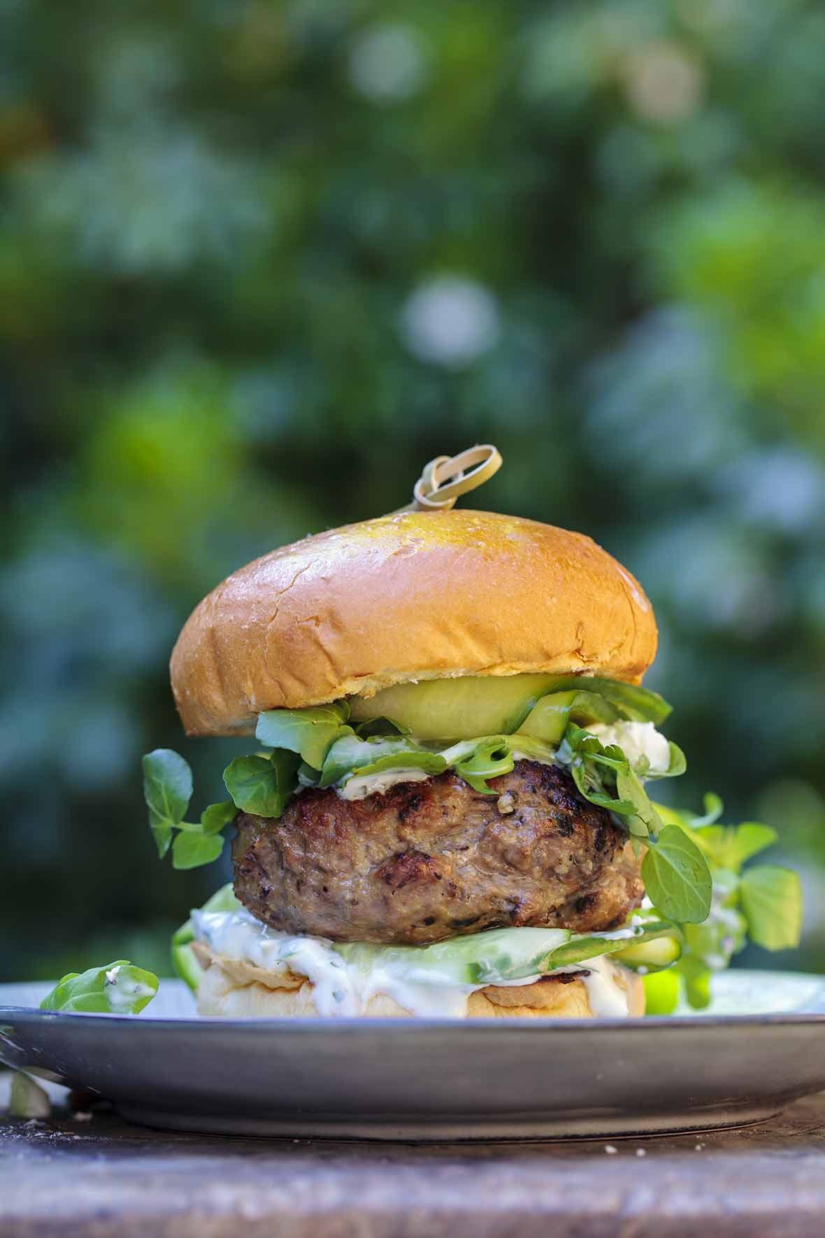 A juicy grilled lamb burger topped with feta cheese, tzatziki, pickles on a bun
