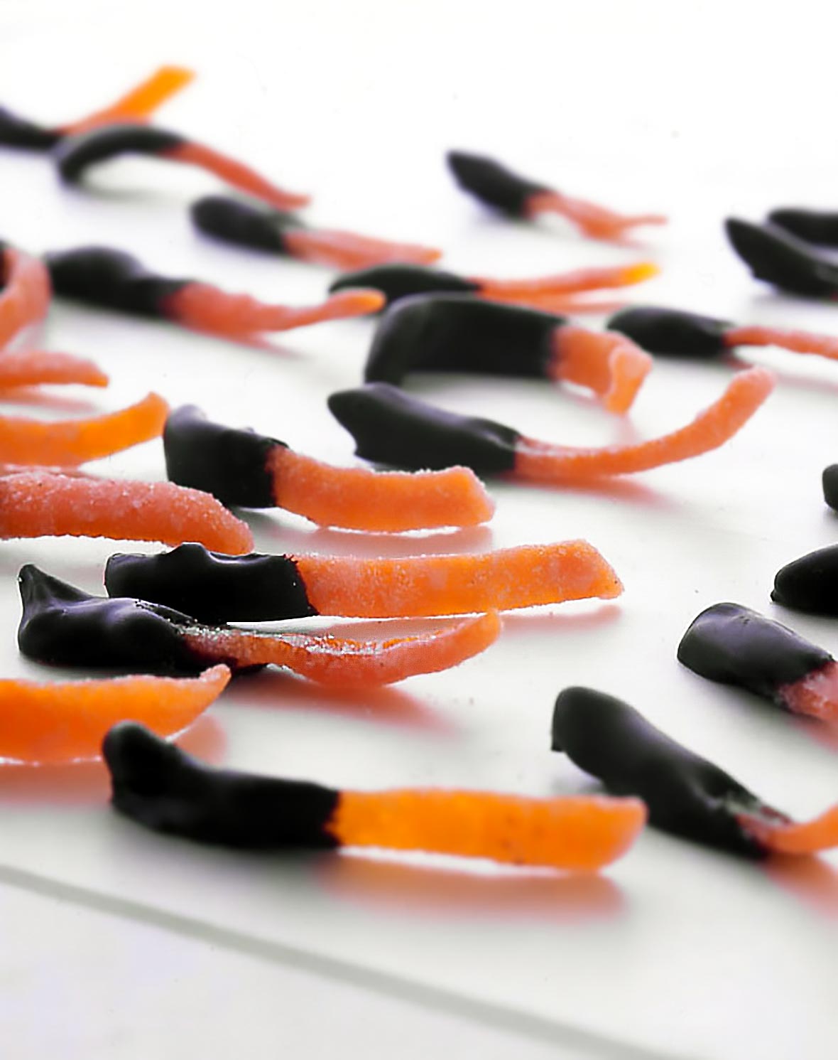Strips of chocolate dipped candied orange peel on a white surface.