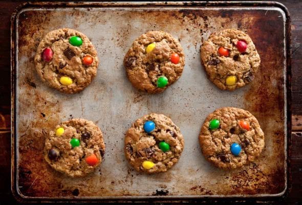 A baking sheet with six peanut butter-oatmeal-chocolate chip cookies studded with M&Ms