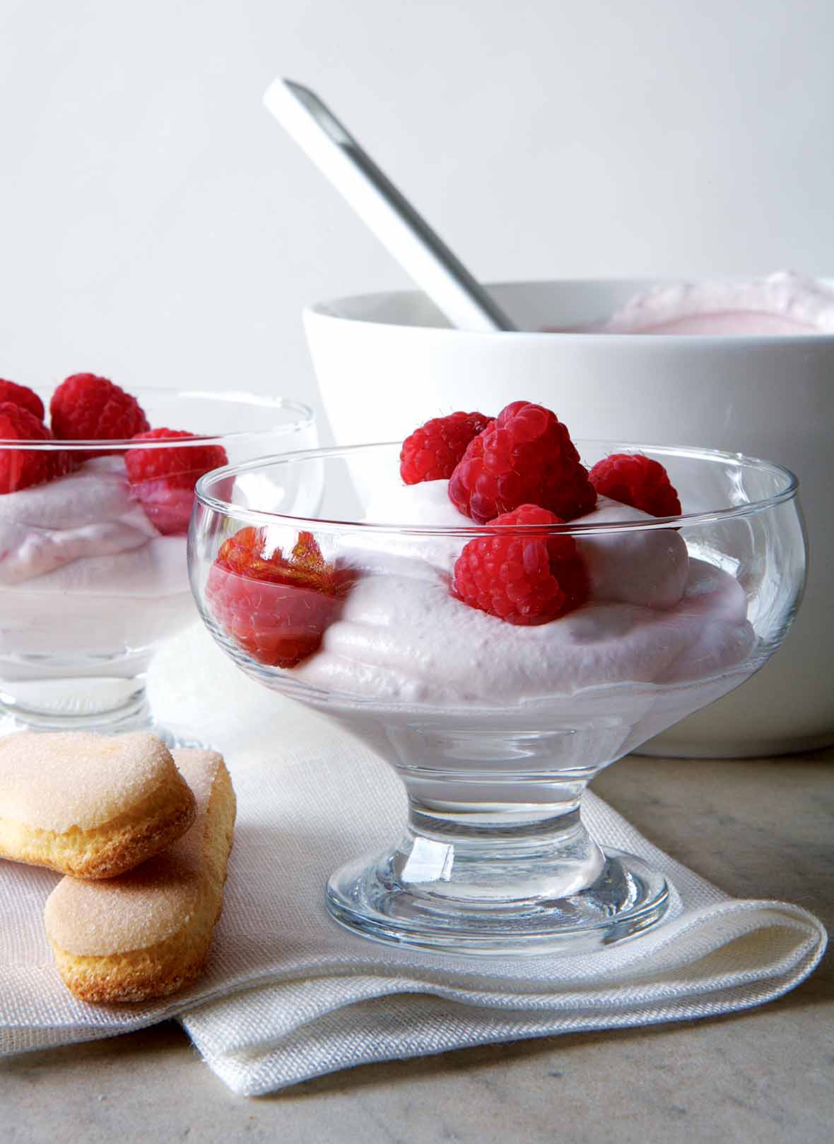 Two parfait-style serving dishes filled with raspberry fool, and topped with fresh raspberries.