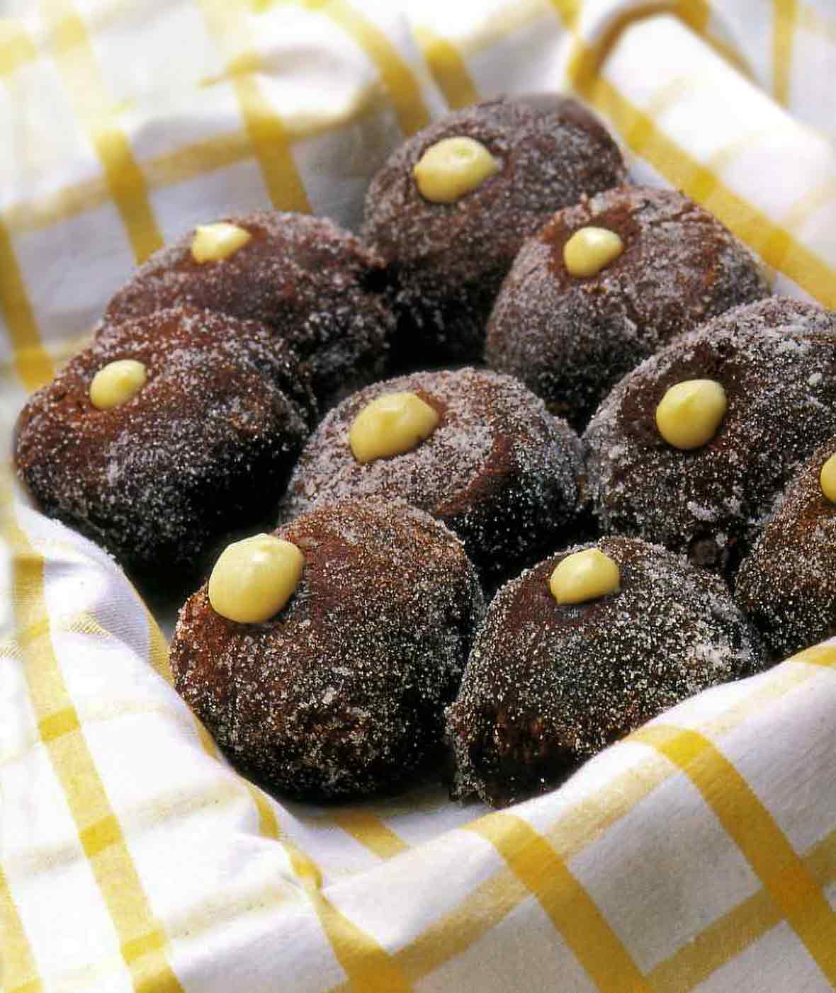 Napkin-lined basket of 9 cream-filled chocolate doughnuts with a dot of pastry cream on each