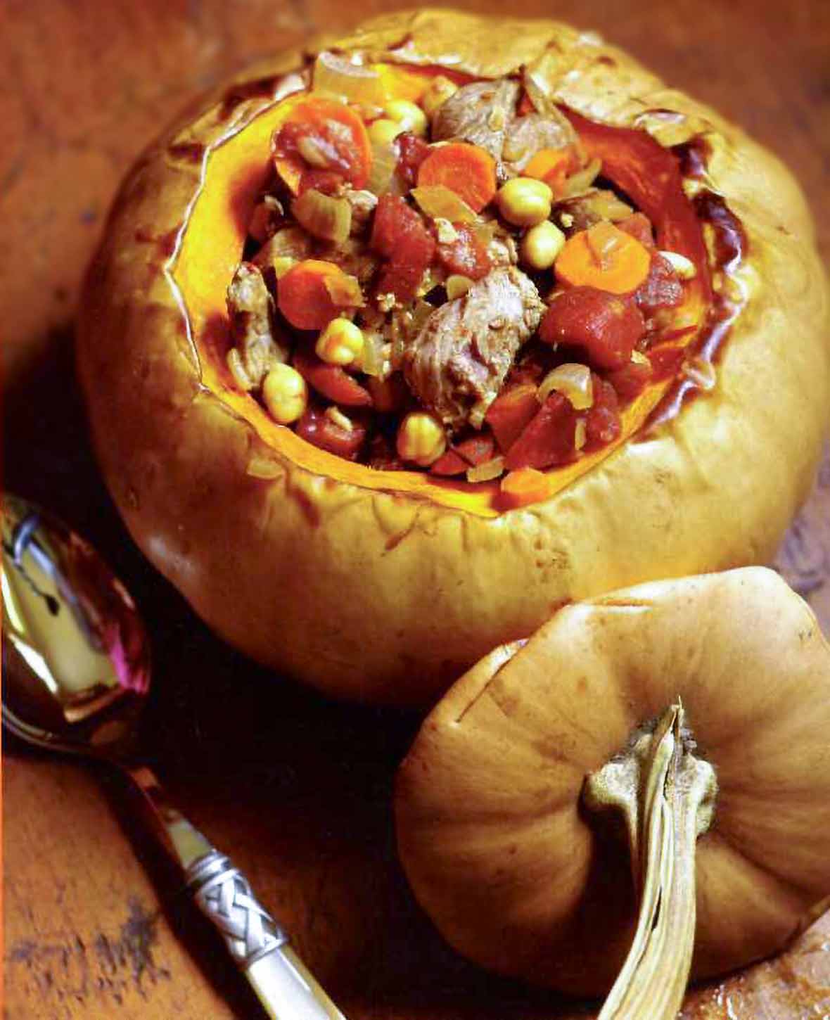Lamb tagine in a whole roasted pumpkin with the top removed; inside chunks of lamb, pumpkin, tomato, chickpeas