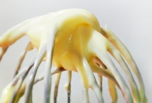 A whisk with homemade mayonnaise on it