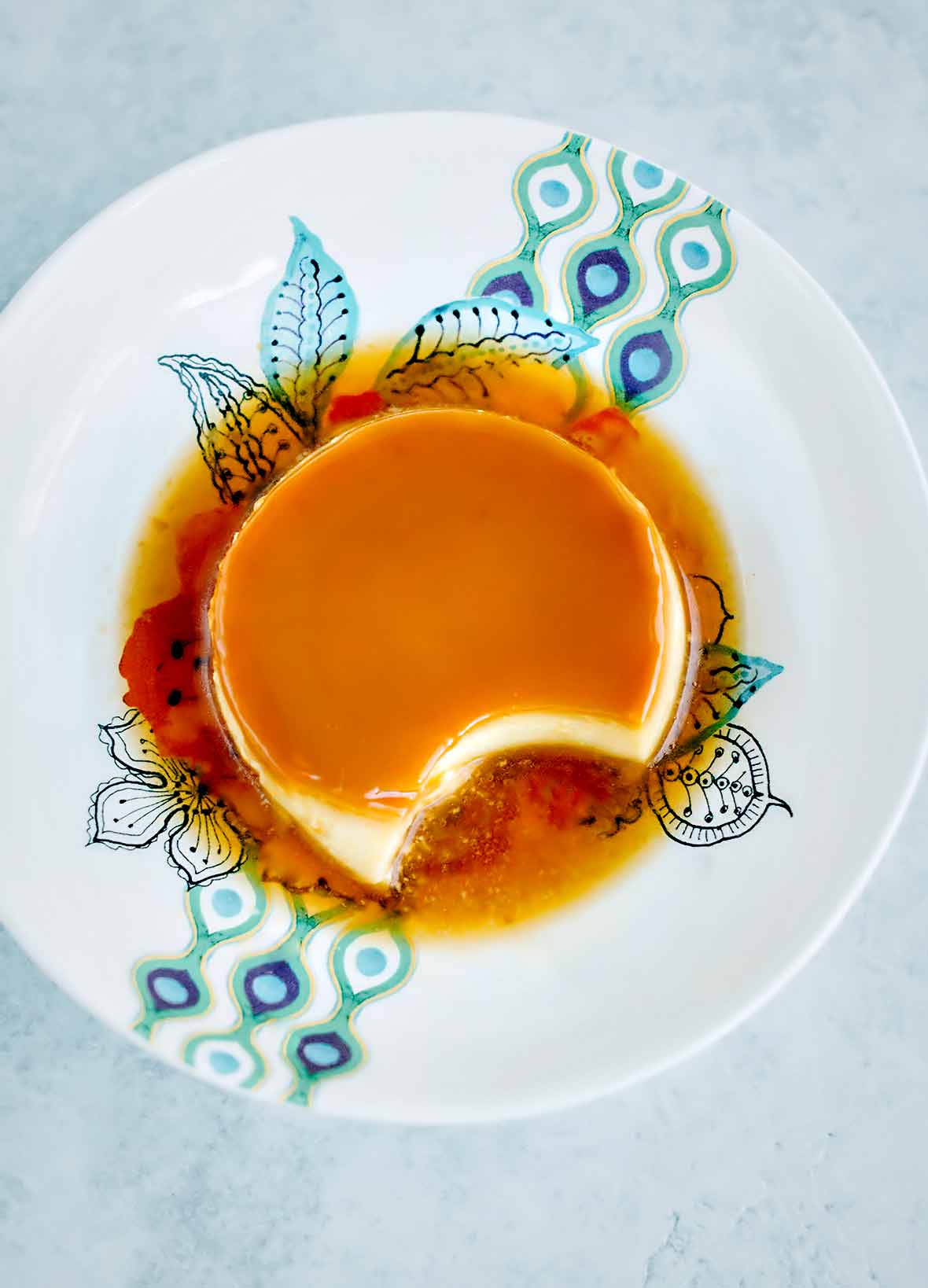 Portuguese tea flan with a caramel top and a puddle of caramel on a white plate with blue design