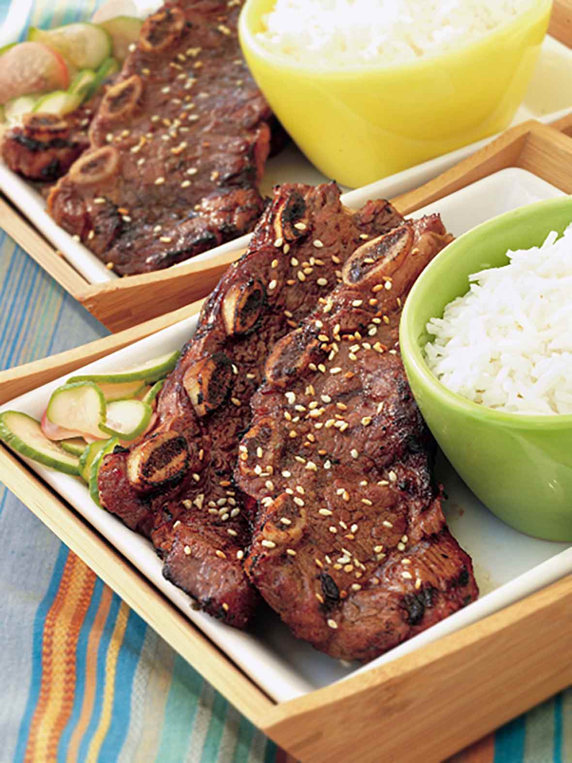 Two slabs of Korean beef barbecue ribs next to a bowl of white rice.