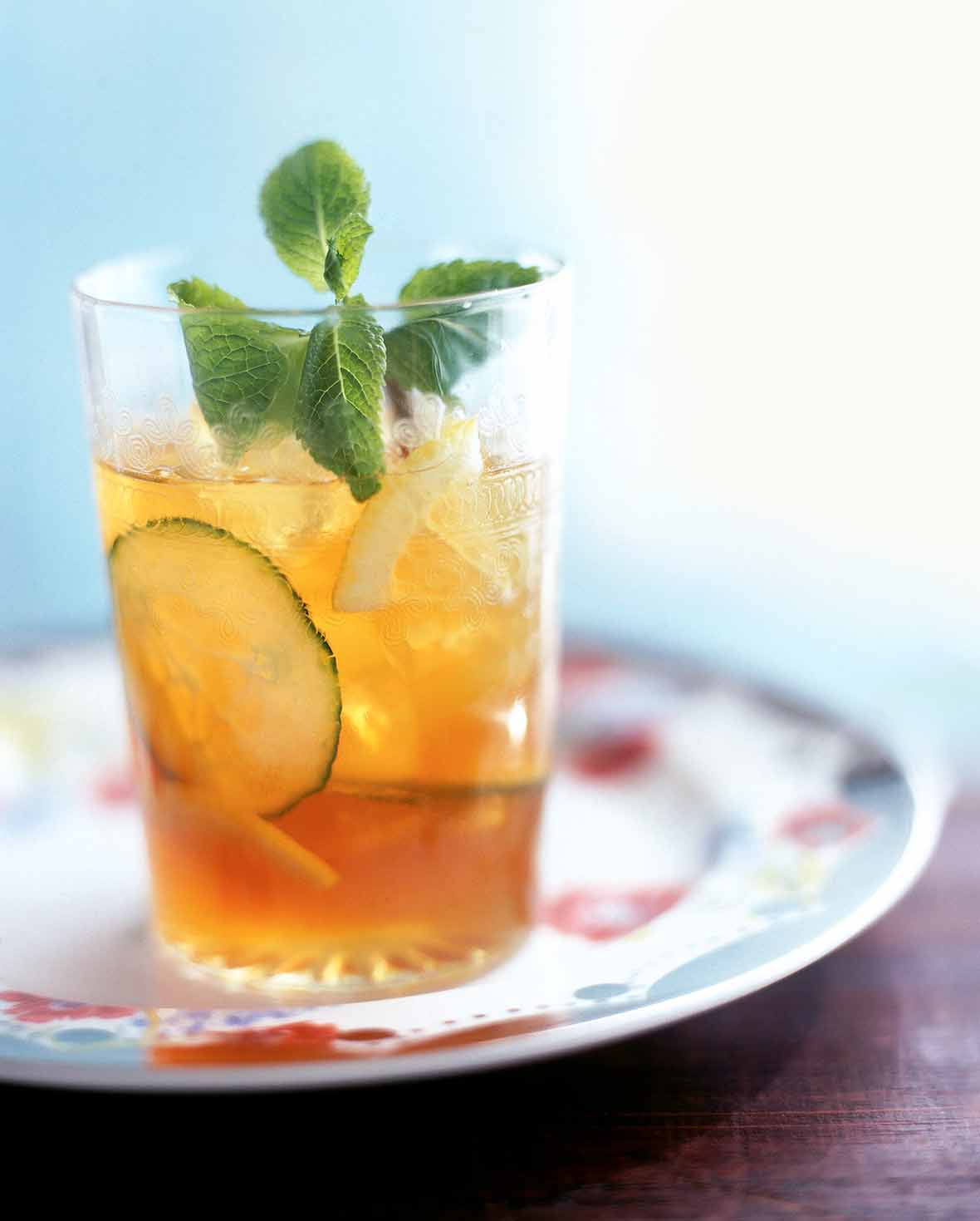 Pimm's Cup cocktail in a class with ice, slice of cucumber, on a flowered tray