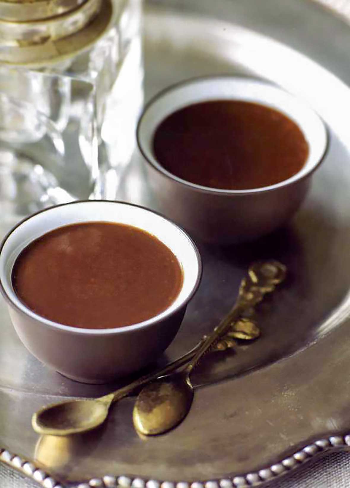 A silver tray with two Turkish coffee creams and two silver coffee spoons.