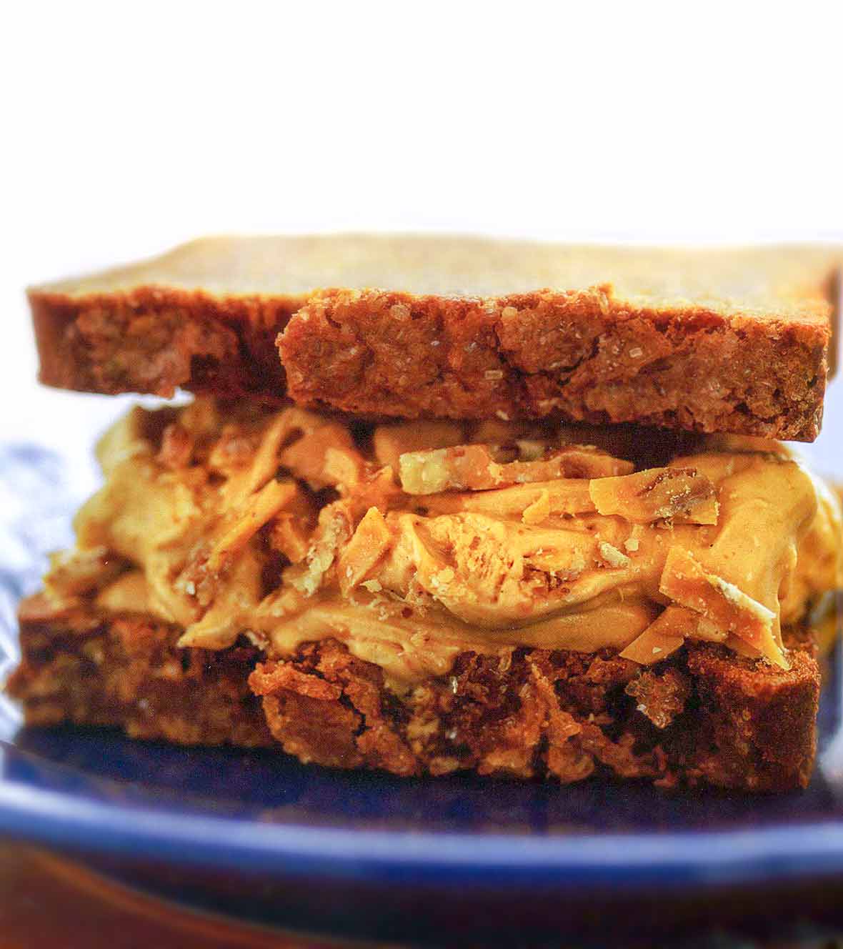 Two slices of banana bread filled with caramel ice cream and pecan brittle on a blue plate