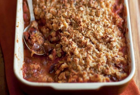 A rectangular casserole dish filled with spicy tomato crumble, and a spoon resting in it.