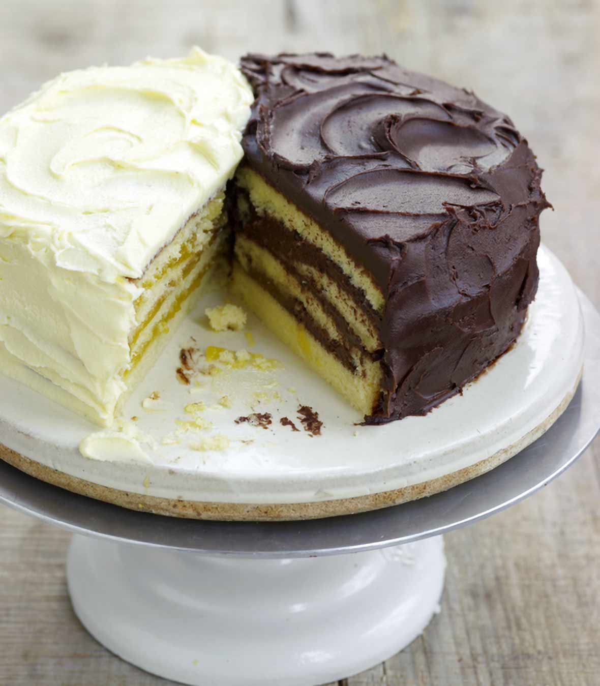 Cake stand with a half of a lemon Doberge layer cake and a half of a chocolate Doberge layer cake