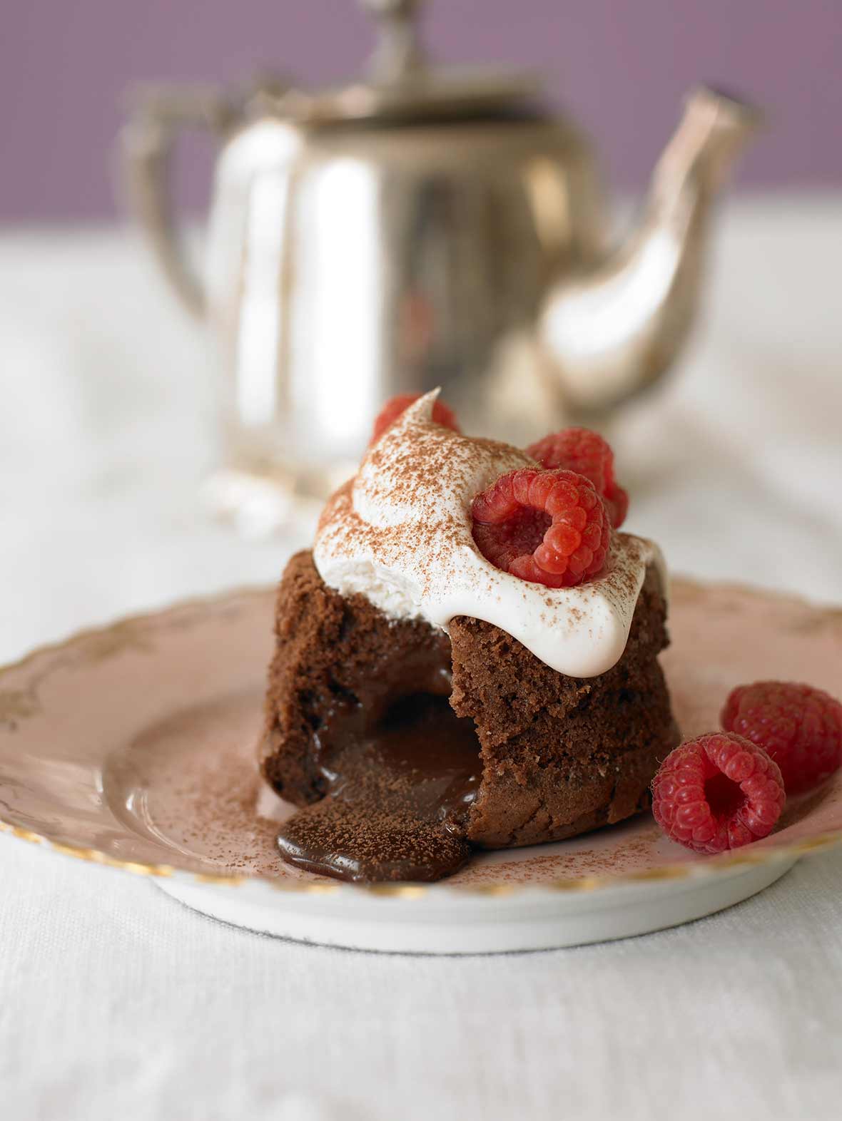 Molten chocolate cake, a wedge cut from it, with chocolate oozing; whipped cream on top, on a plate