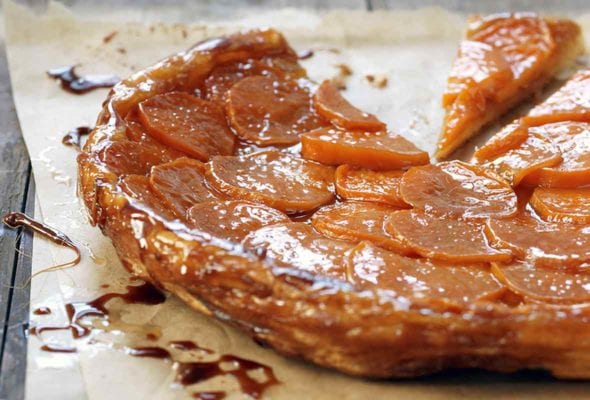 A tart tatin on parchment made with puff pastry crust and on top slices of caramelized sweet potatoes