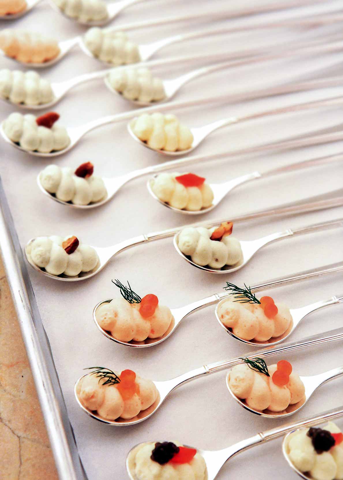 Spoons with smoked salmon mousse, blue cheese mousse, and cauliflower mousse in a baking sheet