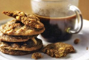 A stack of hazelnut espresso cookies next to a mug of coffee.