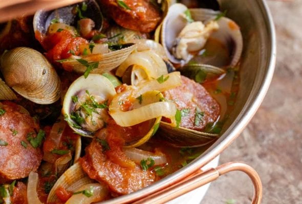 A cataplana with slices of spicy chouriço sausage and sweet clams in a tomato-onion broth
