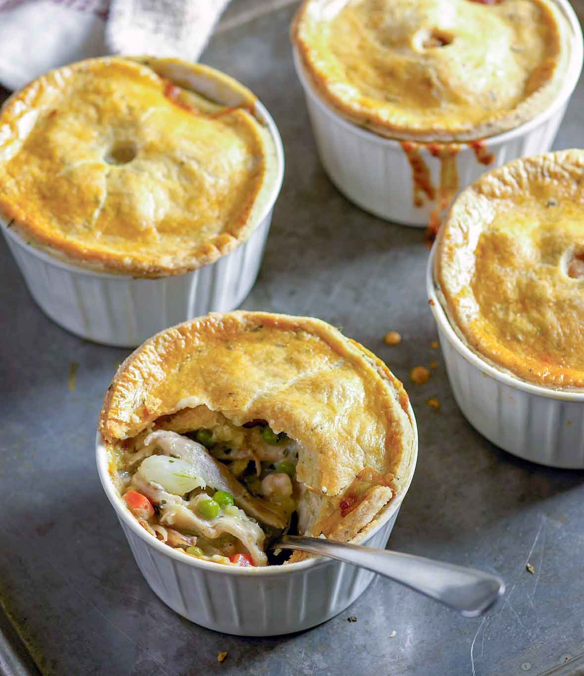Four bowls filled with chopped chicken and vegetables all topped with golden crusts