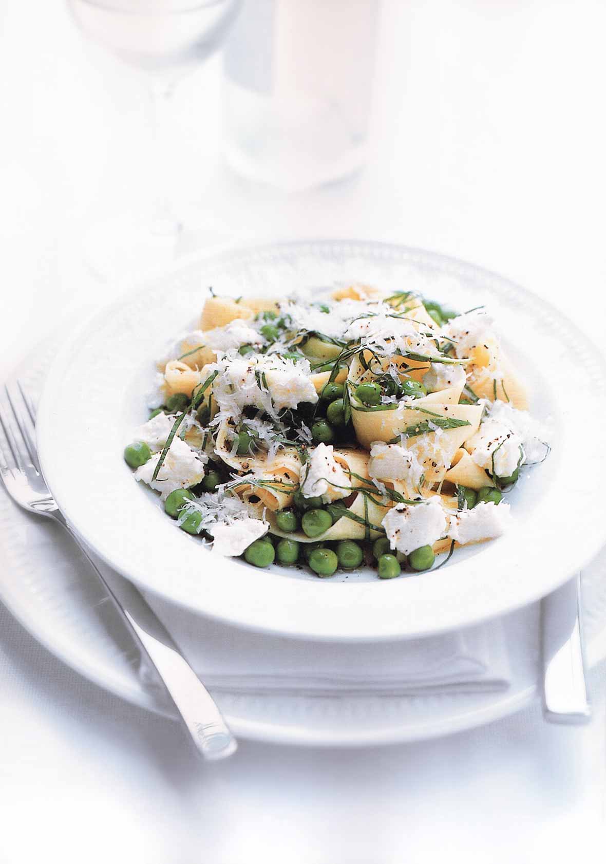A white bowl filled with lemon, ricotta, and pea pasta.