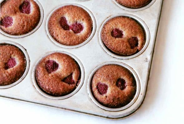 Muffin tin filled with 12 mini-muffin financiers studded with raspberries