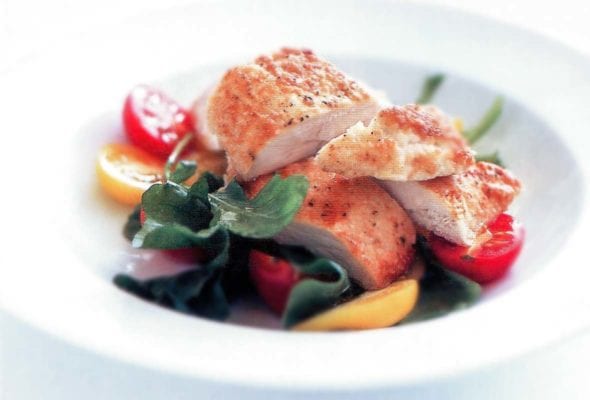 White bowl of sliced parmesan-crusted chicken, lettuce, and red and yellow cherry tomatoes