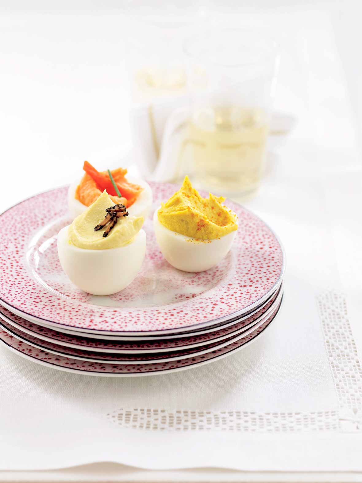 A plate with a trio of deviled eggs - horseradish deviled egg, truffled deviled egg, and smoked salmon deviled egg.