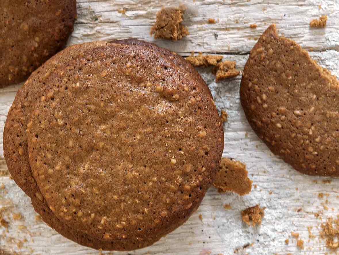 Three Parkins cookies--golden brown British biscuits flecked with oatmeal on white wood