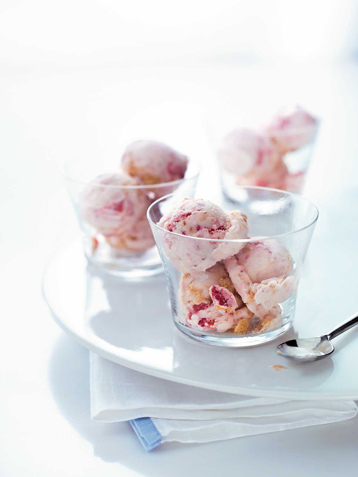 Three glass cups with scoops of strawberry cheesecake ice cream on a plate and dish towel