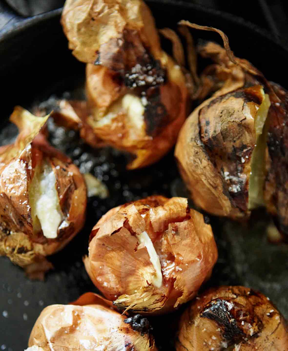 Several whole roasted onions with crispy skin and creamy flesh.