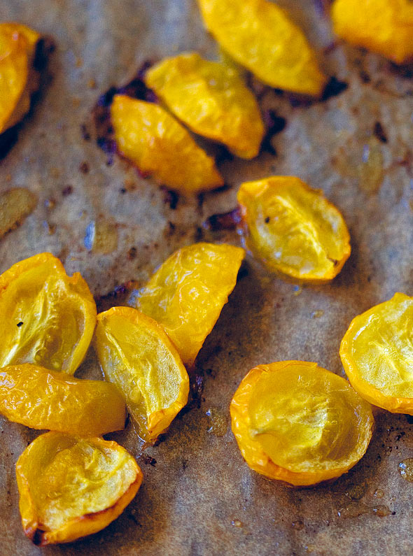 Cut yellow roasted cherry tomatoes on a sheet of parchment paper.