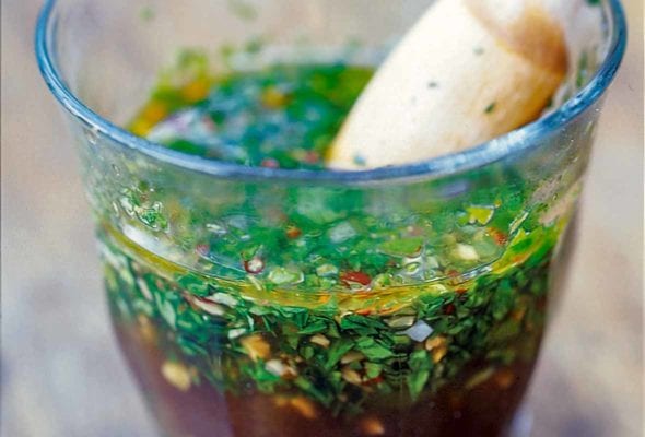 A glass full of chimichurri--an Argentine steak sauce--made with vinegar, olive oil, parsley, oregano, garlic, red pepper flakes