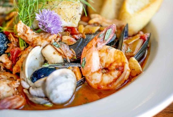 A close up of a white bowl filled with New England bouillabaisse for one.