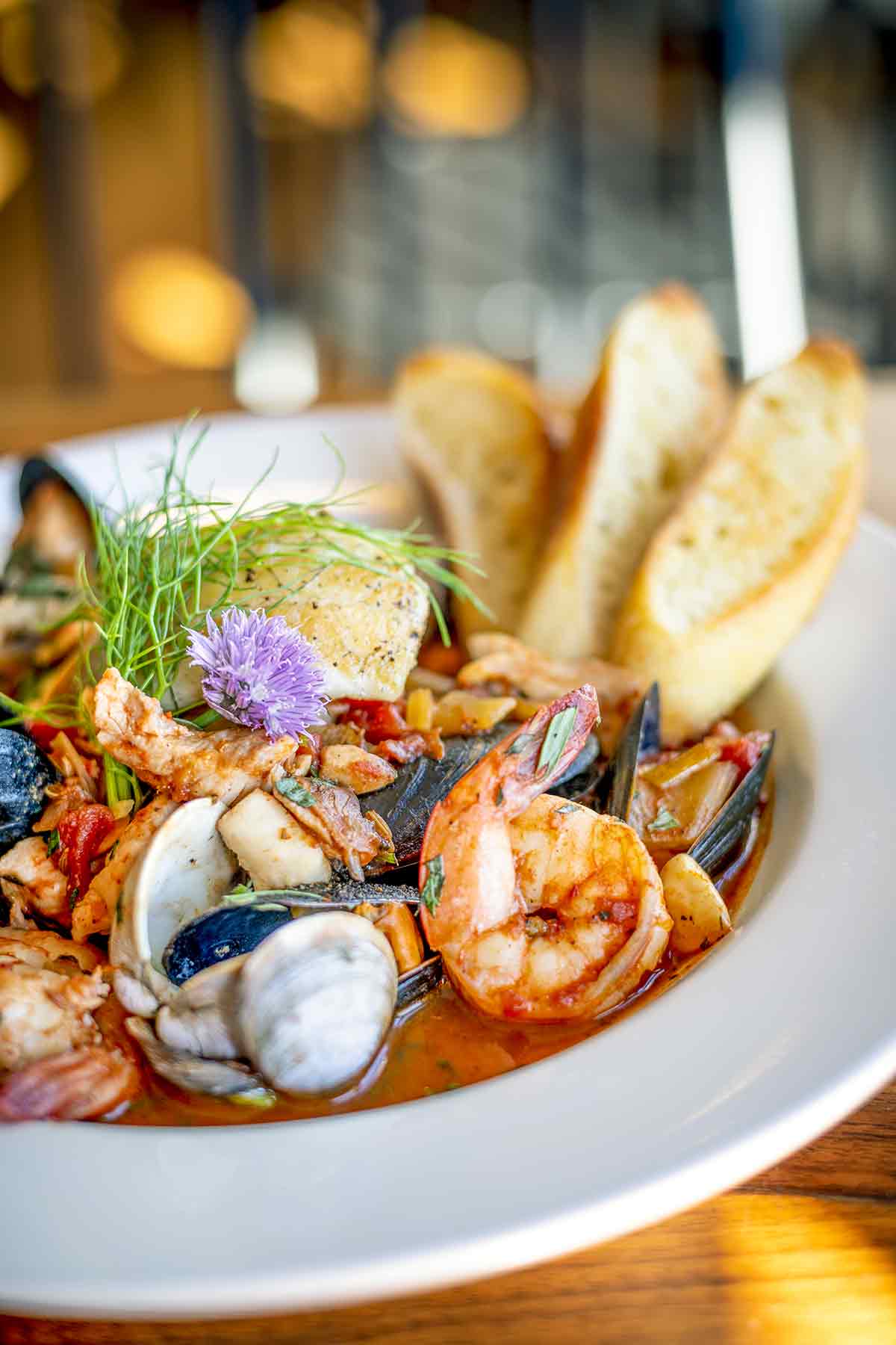 A close up of a white bowl filled with New England bouillabaisse for one.