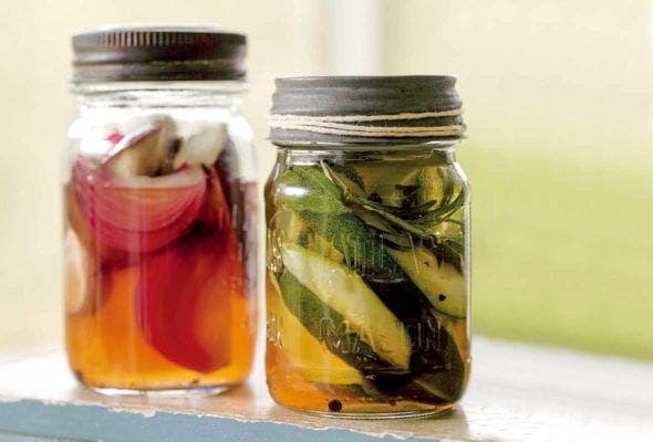 Two jars of ratatouille pickles, one with zucchini, and the other with red onion.