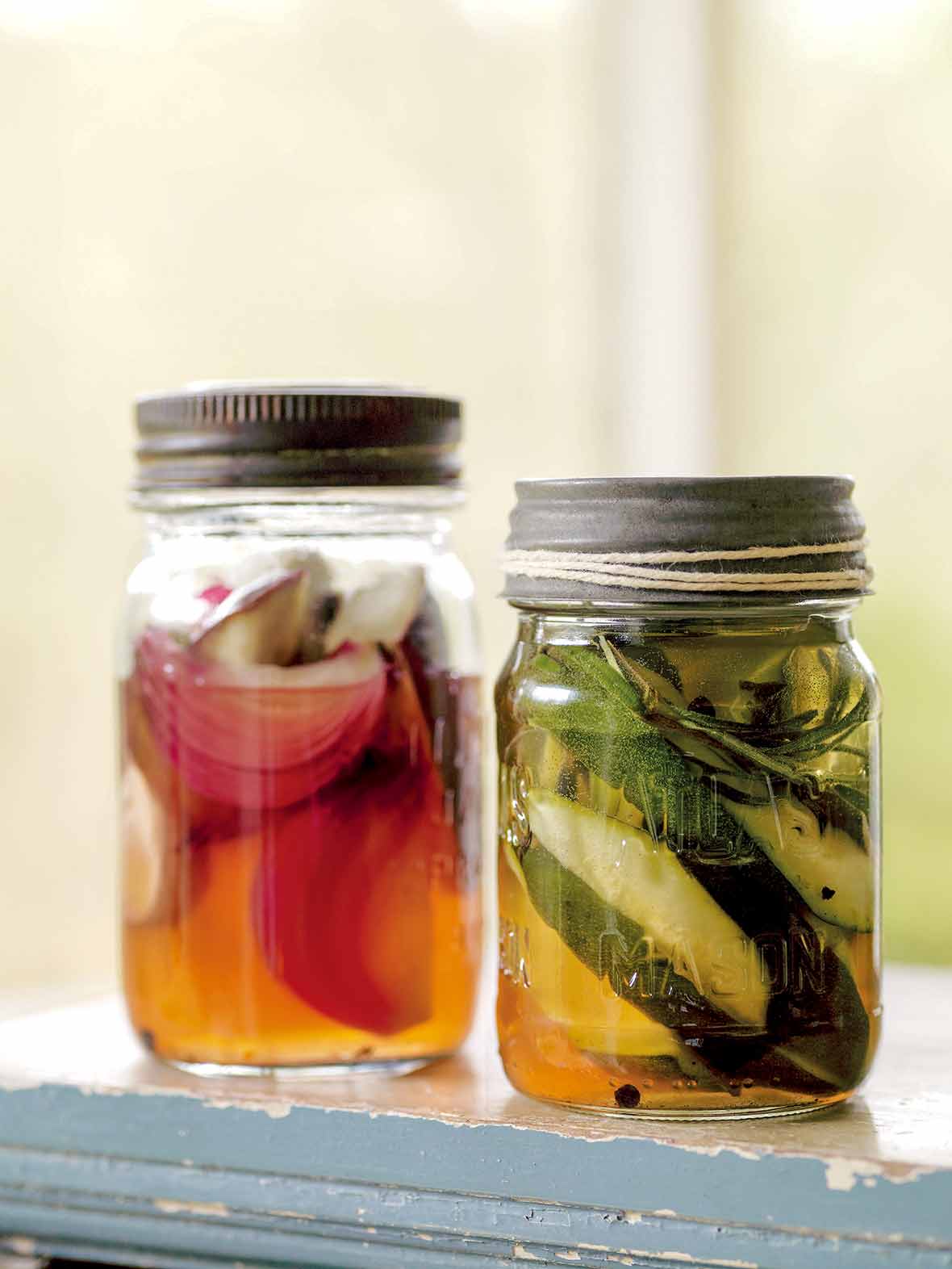 Two jars of ratatouille pickles, one with zucchini, and the other with red onion.